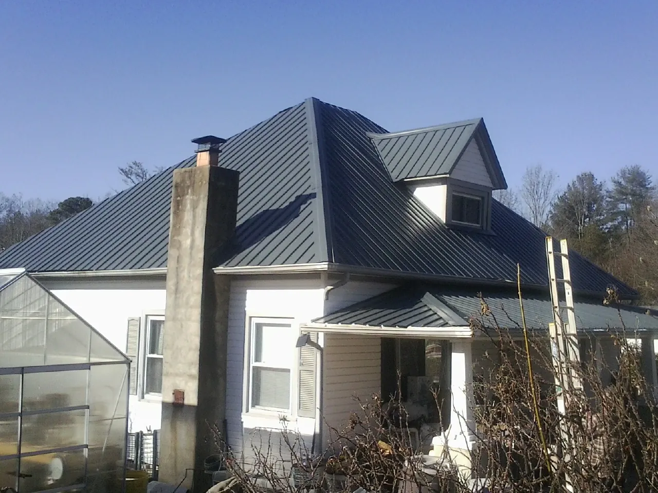 Dark blue standing seam metal roof on a white farmhouse with dormer — Slate & Tile Roof Repair by Roofing Brothers in Rufus