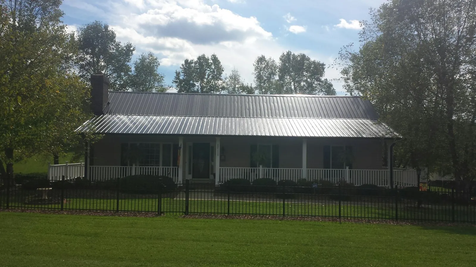 Gray metal roof on a brick ranch with a full width front porch — Gutter Guard Installation work by our crew in Rufus