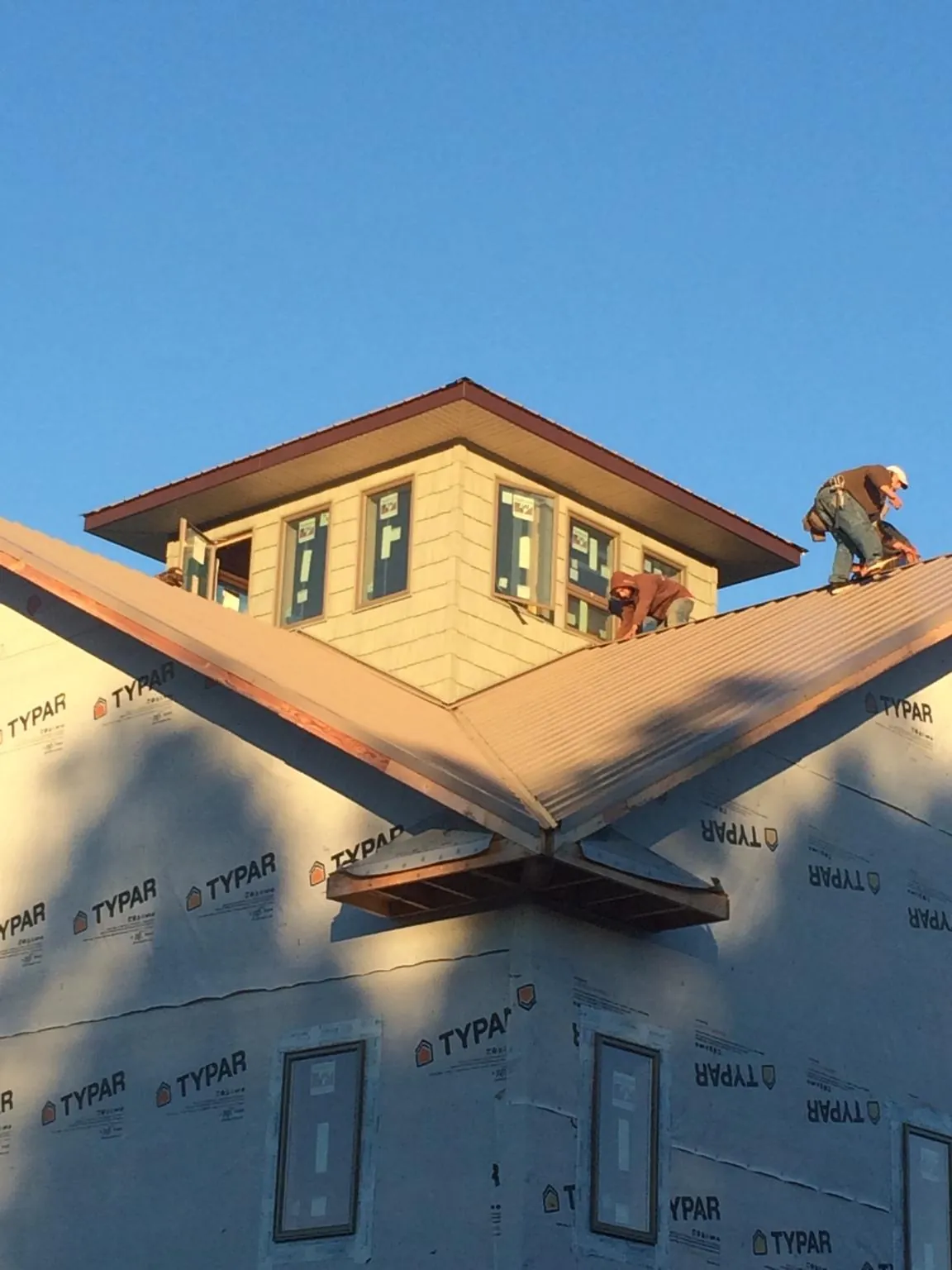 Roofers working around a rooftop cupola on a new metal roof at sunset — Roof Waterproofing in Rufus by Roofing Brothers